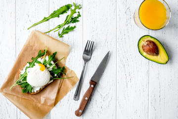 sandwich with poached eggs on wooden background top view