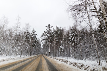 Obraz na płótnie Canvas Asphalt road in the forest in winter
