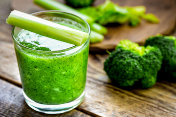 Green vegetable smoothie in glass at wooden background