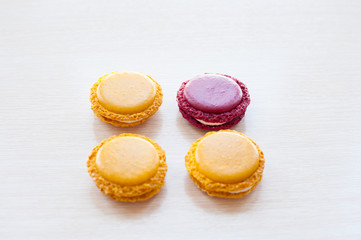 four different-colored round French macaron cookies on the table