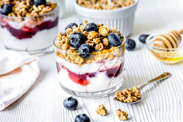 Morning granola with yogurt and berries on white kitchen backgro