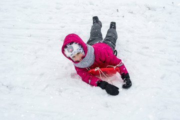 Fototapeta na wymiar Girl in winter clothes on sled