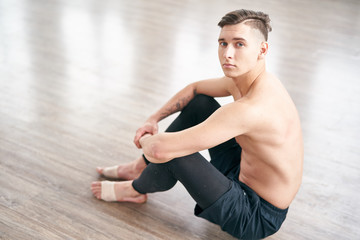 Naklejka premium Handsome ballet dancer sitting on the floor and resting after training.