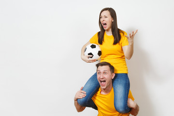 Inspired young couple, woman sit on man shoulders, fans with soccer ball cheering favorite football team expressive gesticulating hands isolated on white background. Family leisure, lifestyle concept.