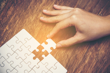 Close up of hand placing the last jigsaw puzzle piece, Hand holding missing jigsaw puzzle piece...
