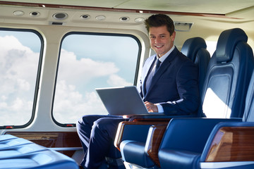 Portrait Of Businessman Working On Laptop In Helicopter Cabin During Flight