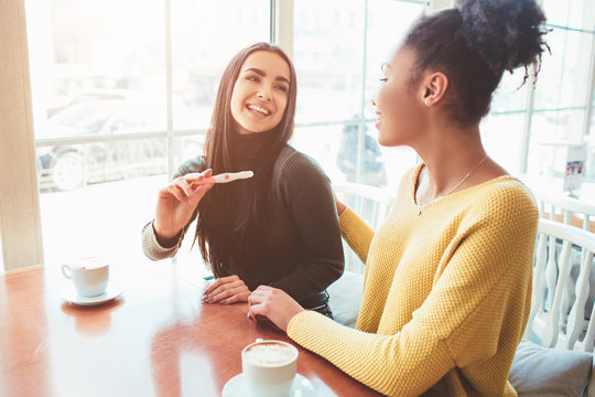An intersting picture of two young girls where one of them is showing her pregnancy test with negative result to the camera. Looks like she is happy about the fact she is pregnant