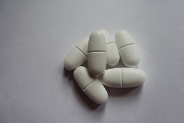 Handful of white oblong caplets of calcium citrate