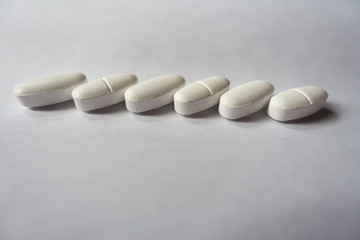 Fototapeta na wymiar Oval pills of calcium citrate in a row