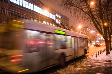 Fototapeta na wymiar The motion of a blurred trolleybus on the street in the evening in the winter