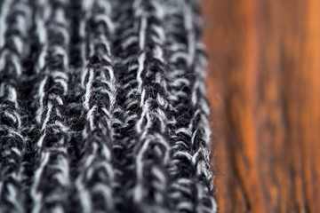 Gray knitted wool product, close up on a wooden background.

