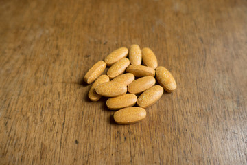 Handful of big multivitamin pills on wood
