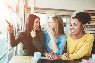 These girls are gossiping Just sitting at the table in cafe and speaking about another man. Young women are amazed and trying to tell one another about what she is thinking about the situation