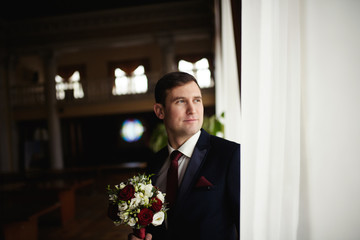 Handsome groom at wedding tuxedo smiling and waiting for bride. Happy smiling groom newlywed. groom at wedding day.