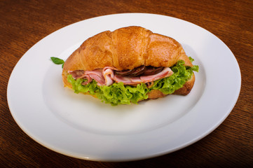 Fresh croissant with ham and salad