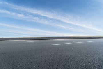 Asphalt pavements and square floor tiles under the blue sky and white clouds