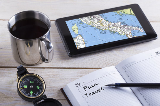 Preparation for traveling concept, cup coffee, compass,the tablet with map,notebook on wooden background.
