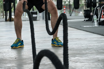 Naklejka premium Fitness trainner show how to play the sport rope equipment in the gym