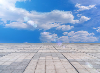 Asphalt pavements and square floor tiles under the blue sky and white clouds