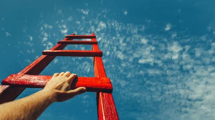 Fotobehang Development Attainment Motivation Career Growth Concept. Mans Hand Reaching For Red Ladder Leading To A Blue Sky © tinyakov