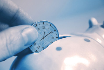 save time pot - human fingers insert coin clock into piggy bank