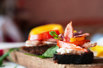 Bruschetta of black bread with beans, cheese, grilled vegetables, peppers and tomatoes and meat