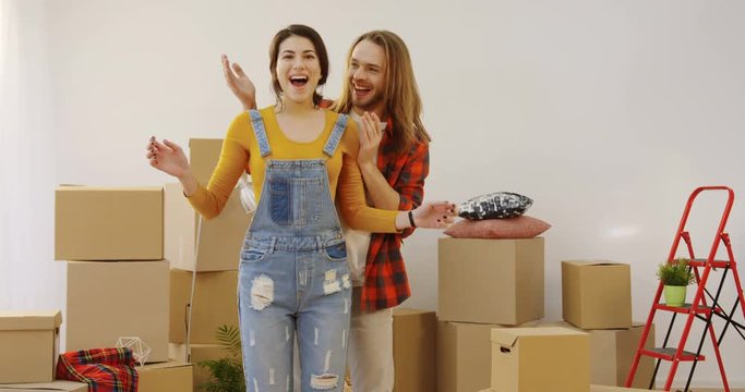 Attractive young man and woman moving in the new house. Man holding his beautiful woman's eyes closed and then showing the cozy room and woman being happy with what she seing. Indoors