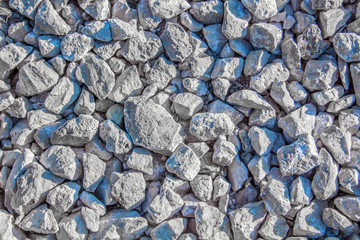 Black-and-white texture of white limestone crushed stone of various sizes.