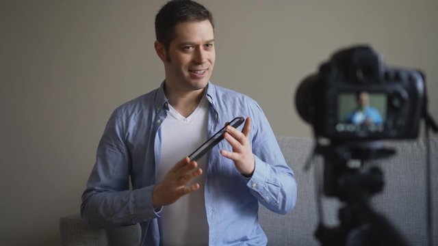 Handsome man making video blog about tablet pc.