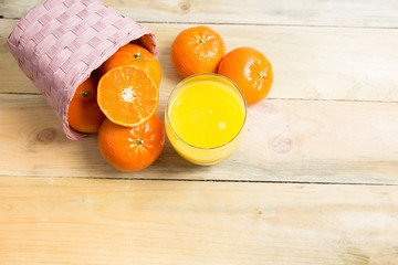 Fresh oranges in basket with a glass of fresh orange juice on wooden bakcground, Top veiw