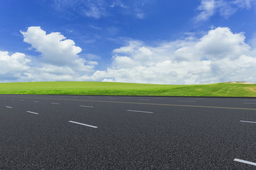 Fototapeta premium Asphalt pavements and prairies under the blue sky and white clouds