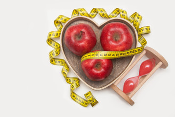 Diet and Healthy Food. Glass Clock and Red ripe Apple in Heart Shape Wooden Box. Cyan Measuring Tape, isolated on white background with copy space. flat Lay.