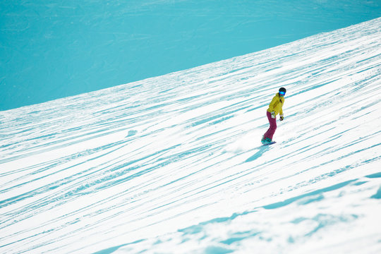 Image of sports girl wearing helmet and mask snowboarding from mountain slope