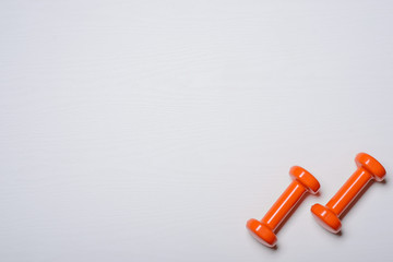 Two dumbbells of orange are lying on a white background with a tree texture