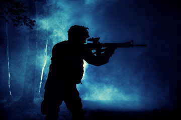 Black silhouette of soldier in the smoke moving in battle operation. Back light, cropped, toned and colorized