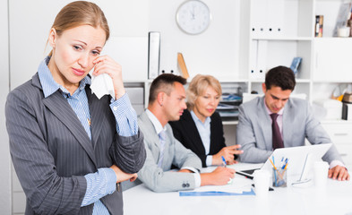 Business woman crying in office with working colleagues