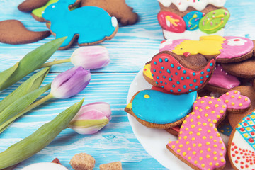 Tulips and gingerbread cookies on white and blue wooden background for Easter.