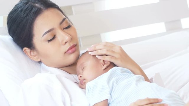 Young asian mother holding with her baby at home. 