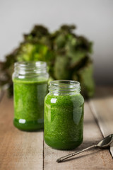 Green spinach juice jar on a rustic wooden table and spoon