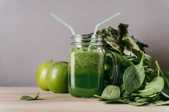 Green detox juice jar with green vegetables with two straws.