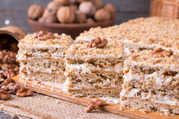 Delicious honey cake with sweet sour cream, and nuts on a rustic background