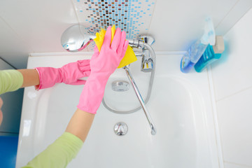 A woman cleaning bath at home. Female washing bathtub and faucet