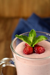Protein cocktail with strawberries and mint in an Irish mug on wooden background