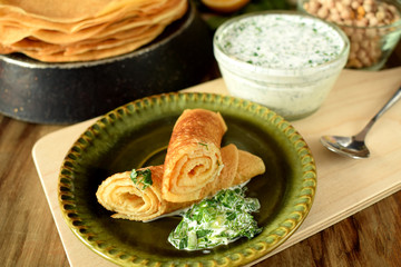 Vegetarian crepes made of chickpea flour with white sauce and greenery