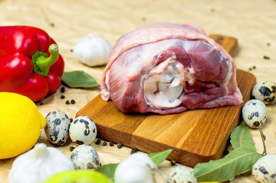 Raw turkey thigh garlic apples lemon quail eggs spices on a wooden board. Top view of a turkey, knife on a beige paper background. Culinary background, ingredients for cooking.