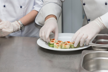Chef is cooking set of sushi on a metal table of restaurant kitchen. Selective focus. Shallow depth of field