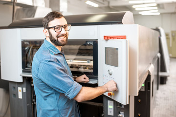 Printing operator working with offset machine at the printing manufacturing