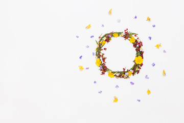 Wreath from summer field flowers on white background with violet and yellow flowers around