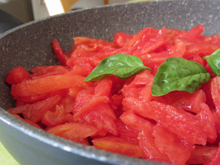 Cooking homemade tomato sauce using fresh summer tomatoes, onion, garlic and basil. Italian recipe