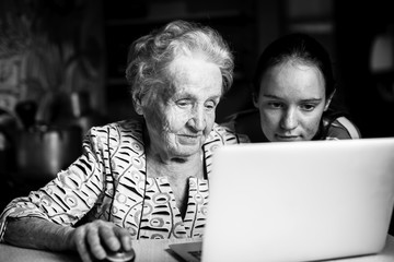 Teen girl teaches her grandmother to type on the laptop.